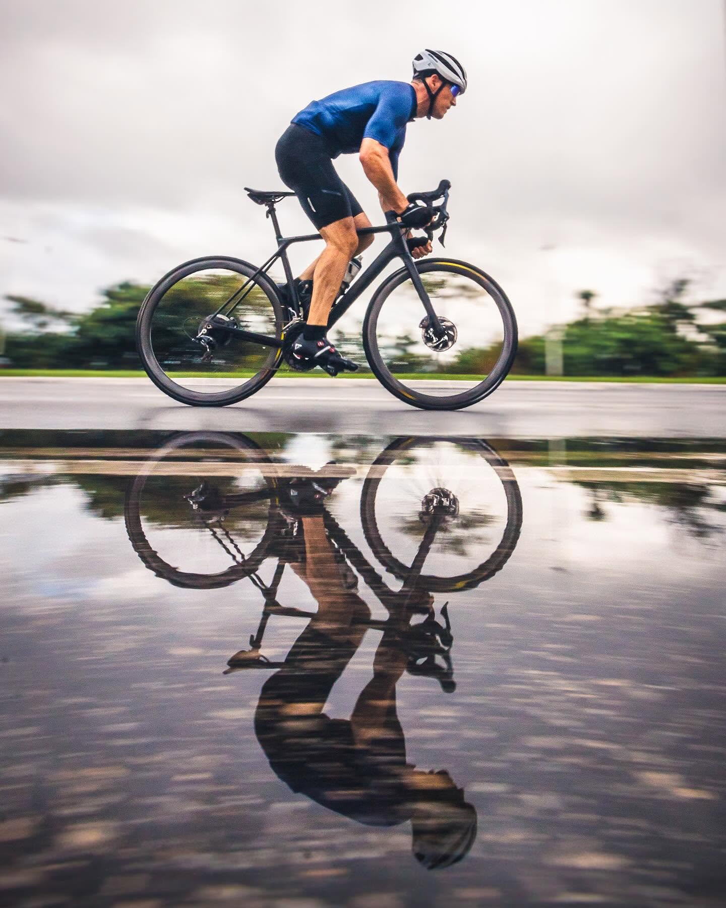 Pedalada em estrada molhada, com o reflexo na poça d'água
